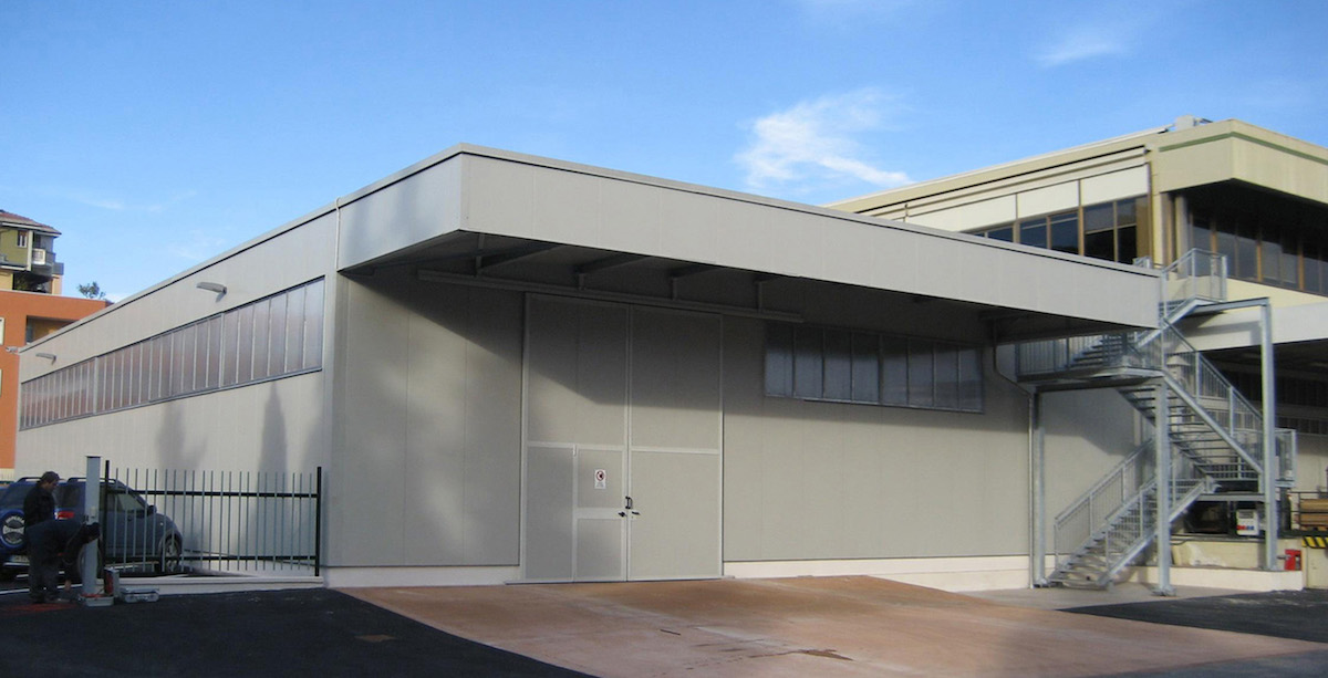 Salone industriale con struttura metallica in ferro e scala di sicurezza laterale.